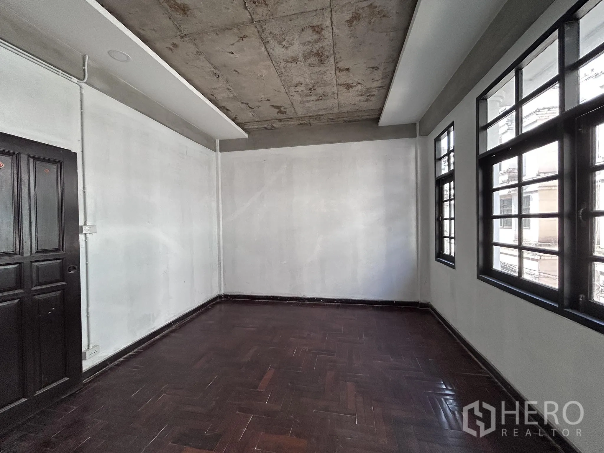 家庭办公室 for rent or sale in Watthana, Bangkok - 多扇格栅窗的房间，深色木地板与门口。