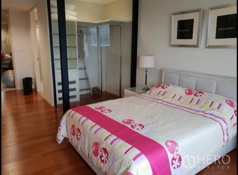 Condominium for rent in Sathon, Bangkok - Primary bedroom with double bed, wood floors and glass-walled closet.