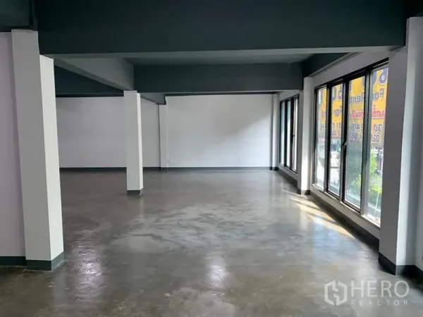 Shophouse for rent in Khlong Toei, Bangkok - Open-plan retail floor with polished concrete flooring, white walls and full-height windows bringing in natural light.