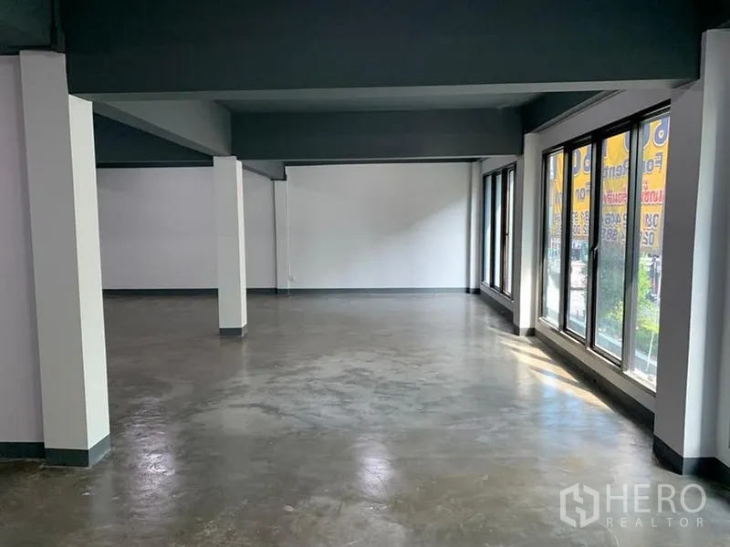 Shophouse for rent in Khlong Toei, Bangkok - Open-plan retail floor with polished concrete flooring, white walls and full-height windows bringing in natural light.