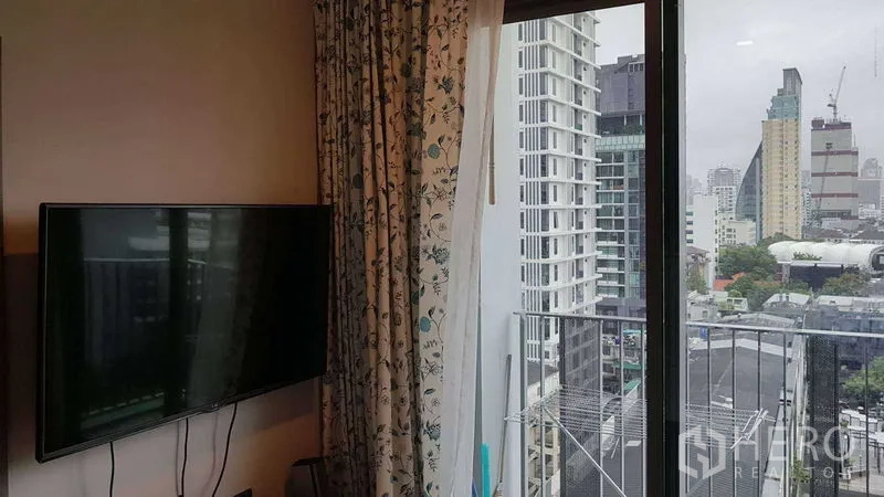 คอนโด ขายในWatthana, Bangkok - มุมนั่งเล่นติดทีวีแขวนผนัง ประตูบานเลื่อนออกสู่ระเบียง เห็นวิวสกายไลน์เอกมัย