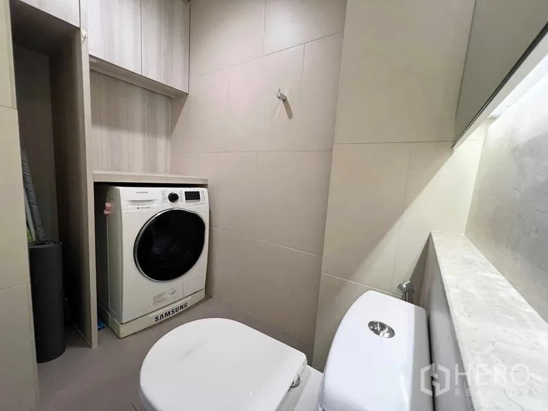 Condominium for rent or sale - Second bathroom with washing machine niche, storage cabinet, and toilet.