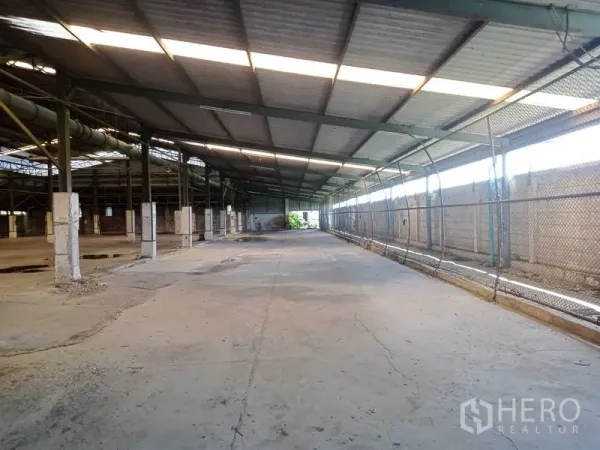 Factory for rent in Lat Lum Kaeo, Pathum Thani - Covered loading and staging area with long concrete drive, chain‑link side wall and ventilated roof.