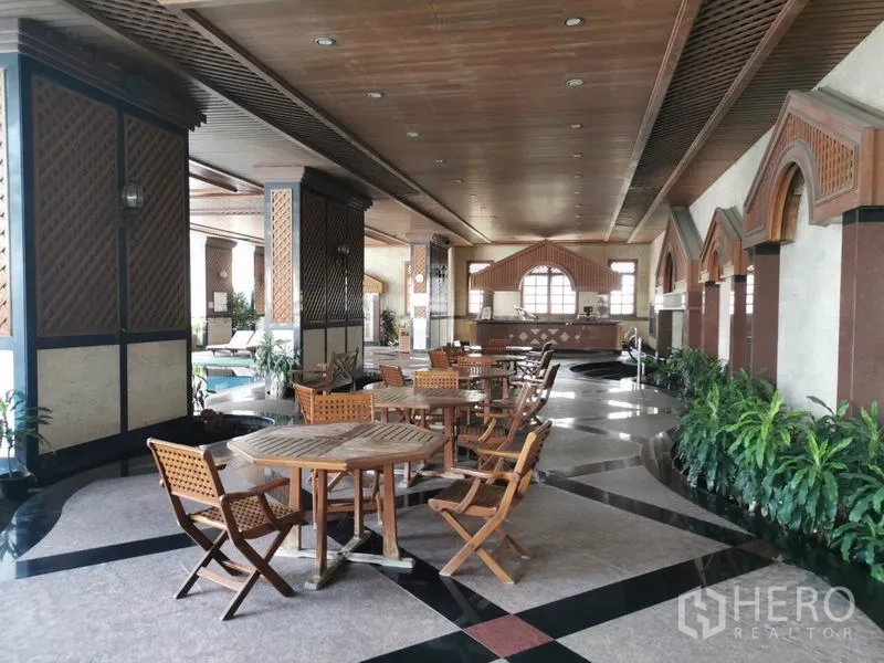 公寓 出租在Watthana, Bangkok - 泳池旁遮荫休闲区，摆放木质桌椅。