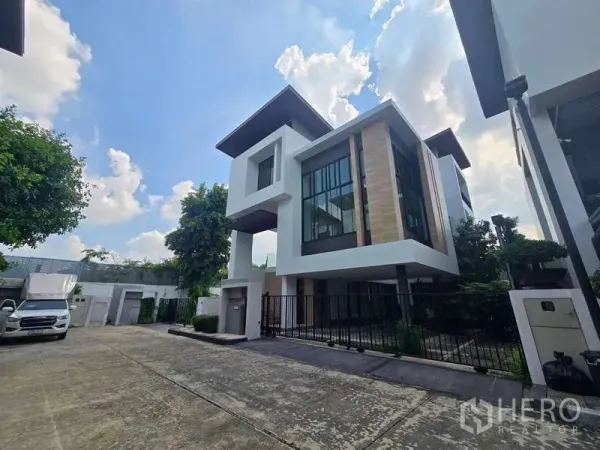 บ้าน ให้เช่าในBueng Kum, Bangkok - บ้านเดี่ยวสไตล์โมเดิร์นสูง 3 ชั้น หน้าต่างบานใหญ่ ที่จอดรถมีรั้วรอบ และบรรยากาศร่มรื่น
