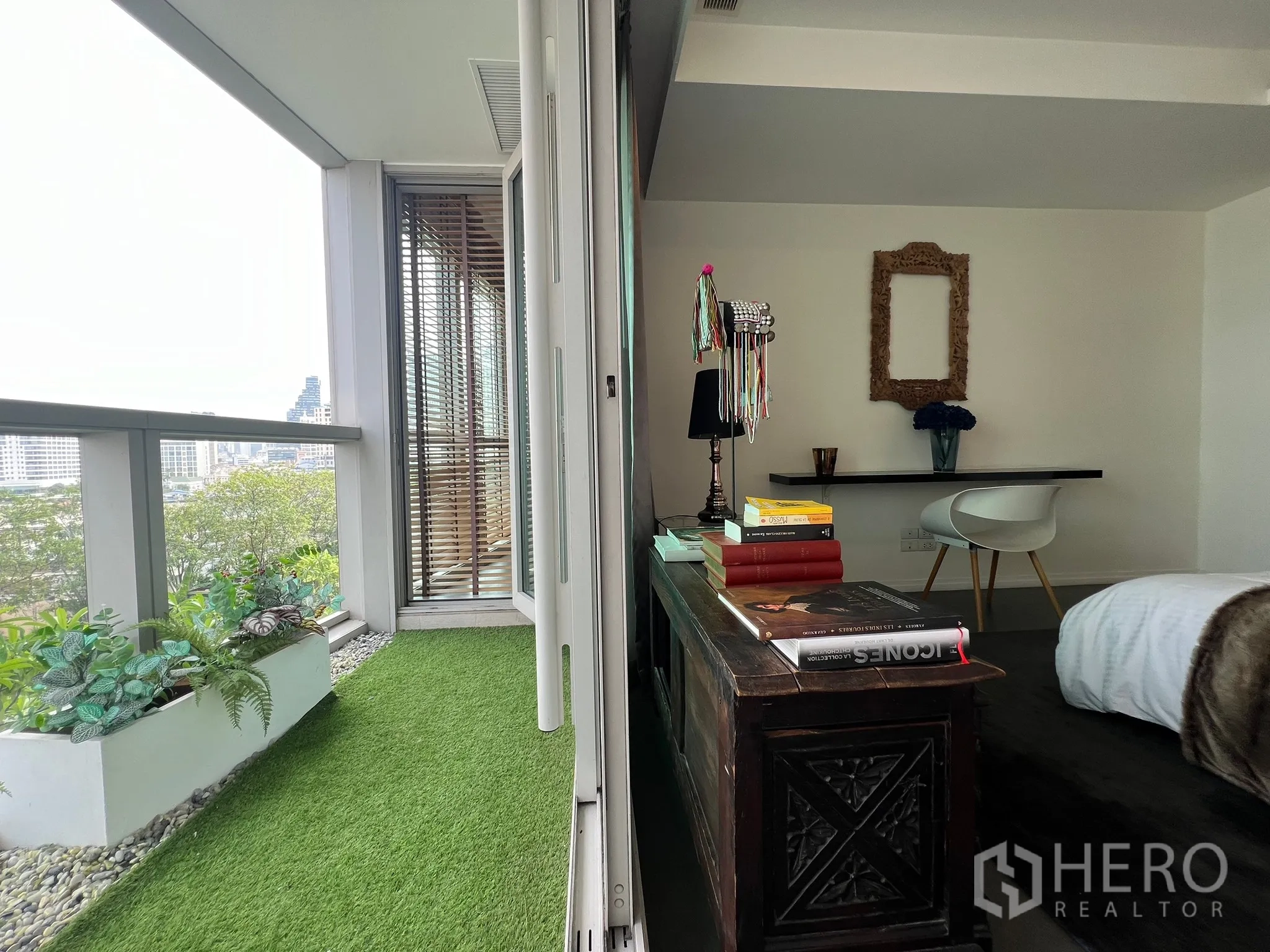 Condominium for sale in Khlong San, Bangkok - Bedroom opening to a balcony with artificial grass and planter boxes.