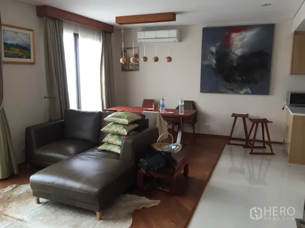 Condominium for rent in Ratchathewi, Bangkok - Bright living room with wood flooring, leather sofa, dining set, pendant lights and large curtained windows.
