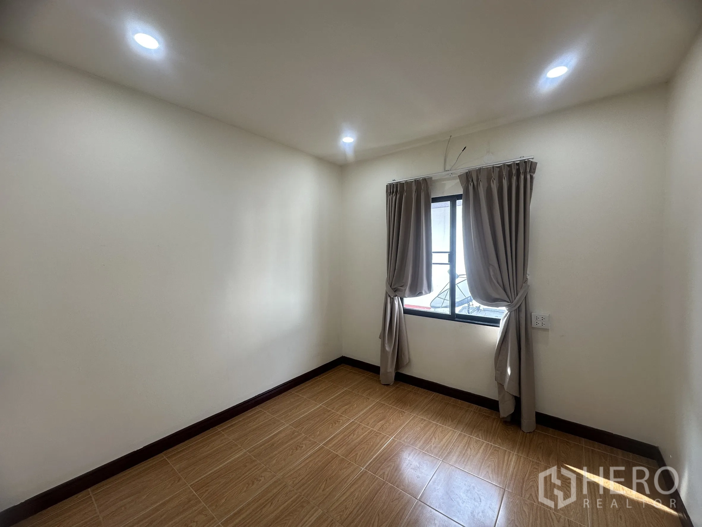 Townhouse for sale in Lam Luk Ka, Pathum Thani - Additional bedroom with two curtained windows and tiled floor.