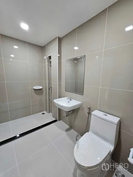 Townhouse for rent in Bang Kapi, Bangkok - Modern bathroom with walk-in shower, wall tiles, pedestal sink and toilet.
