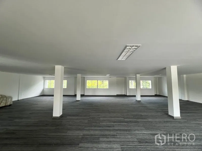 Retail Space for rent in Huai Khwang, Bangkok - Spacious open‑plan retail floor with white columns, carpet tiles, and ceiling lighting with natural light from multiple windows.