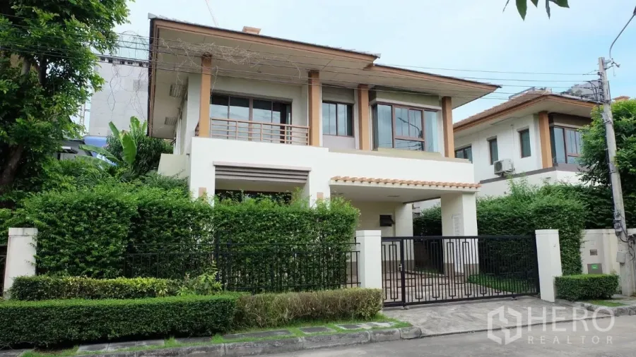 Detached House for sale in Bang Phli, Samut Prakan - Two-storey detached house with gated entrance, balcony and lush hedge frontage.
