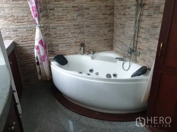 公寓 出租在Watthana, Bangkok - 浴室设转角按摩浴缸，双头枕与石纹墙面，配手持花洒。