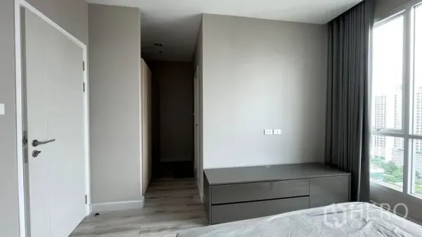 Condominium for sale in Sathon, Bangkok - Minimal bedroom corner with built-in dresser, white doors and a floor-to-ceiling window.