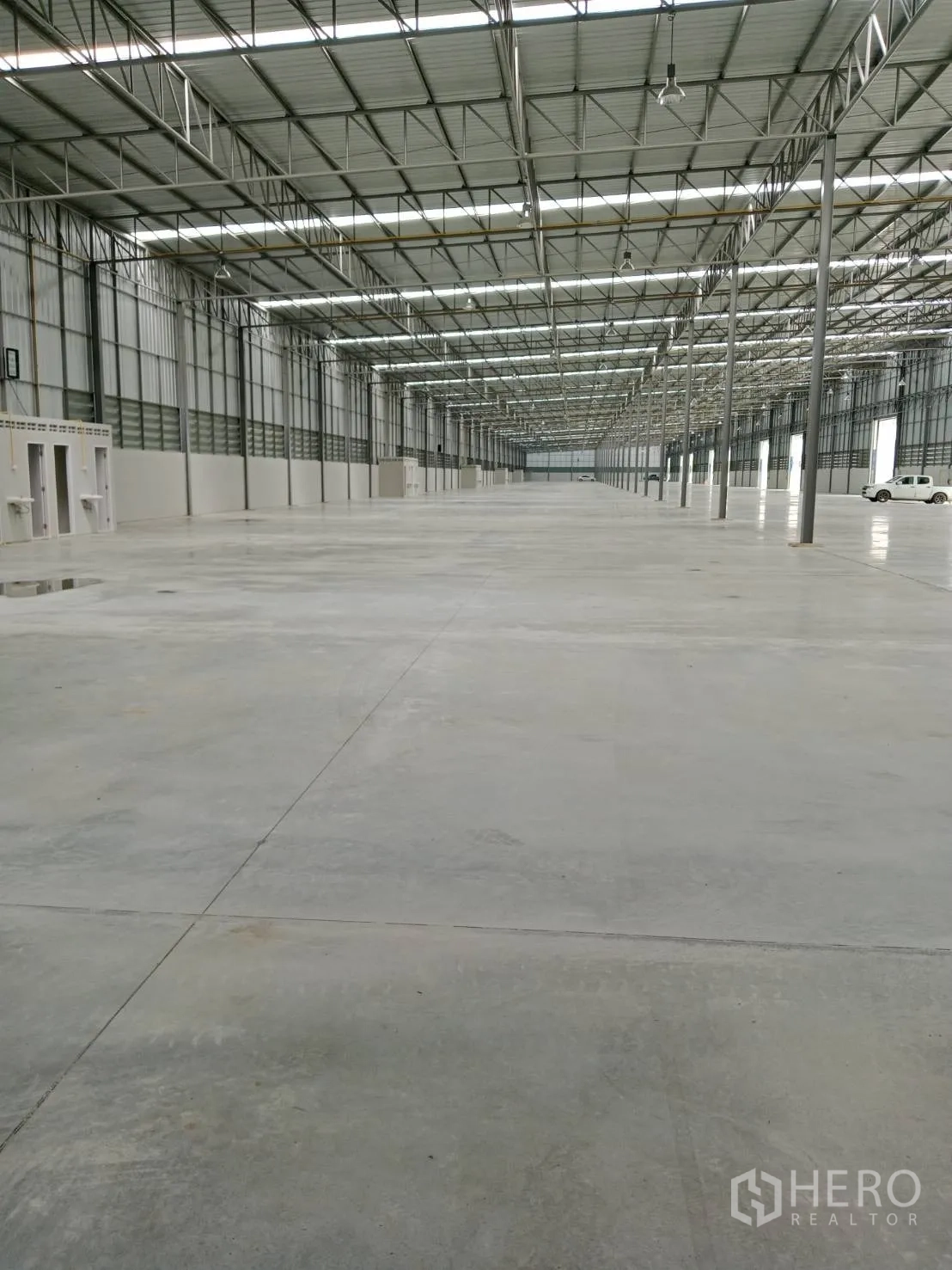 Warehouse for rent in Lat Krabang, Bangkok - Warehouse interior showing side service rooms, wide aisle, and a vehicle near the loading area.