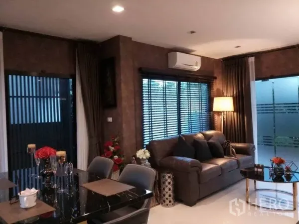 独立式住宅 出售在Nonthaburi - 开放式客餐厅，皮沙发、空调与大面积窗户。