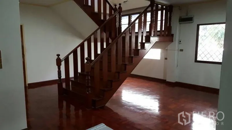 Detached House for rent in Khlong Toei, Bangkok - Open-plan living area featuring a solid wooden staircase and large windows.