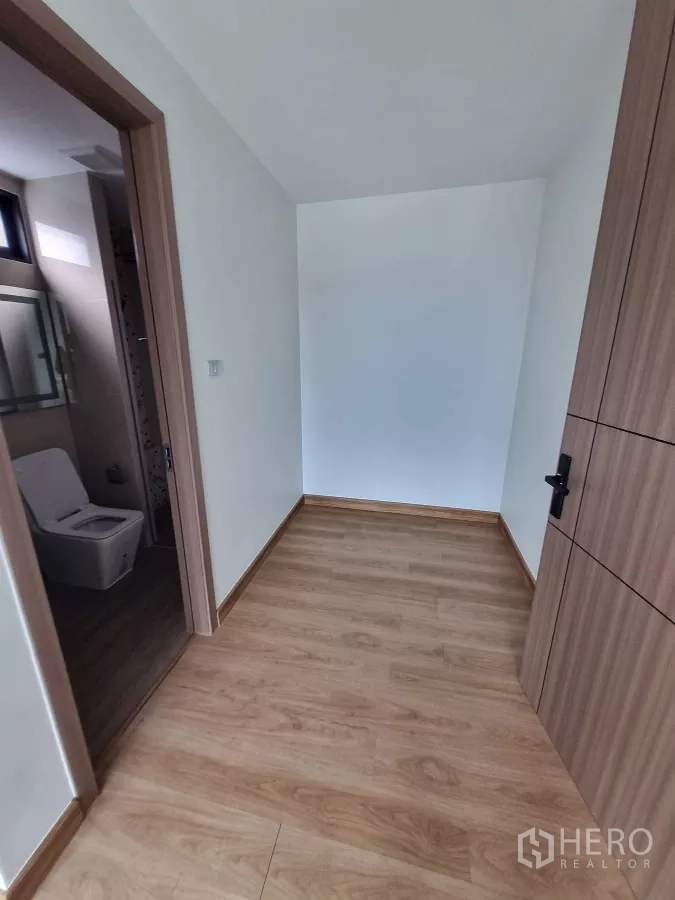 Home Office for rent in Khlong Toei, Bangkok - Compact hallway or dressing nook with wood flooring next to a bathroom.