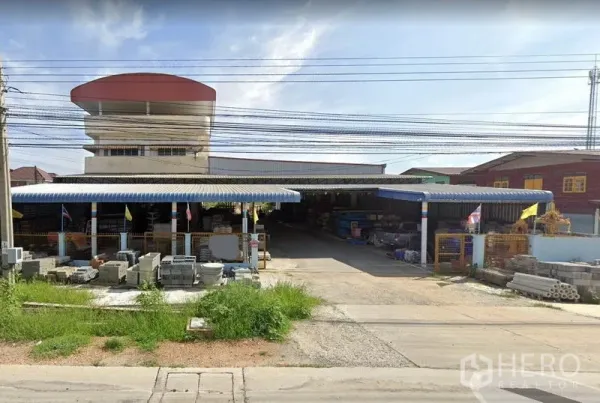 คลังสินค้า ให้เช่าในSai Noi, Nonthaburi - ด้านหน้าโกดังในไทรน้อย หลังคาเมทัลชีทสีน้ำเงิน ทางเข้ากว้าง และวัสดุก่อสร้างวางเรียง
