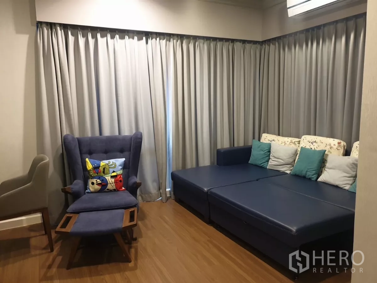 独立式住宅 出租或出售在Prawet, Bangkok - 二层起居区，蓝色沙发、翼背椅与整面窗帘