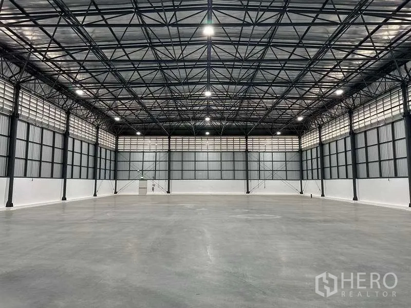 Factory for rent in Bang Sao Thong, Samut Prakan - Clear-span warehouse hall with insulated roof panels and louvered side windows for ventilation.