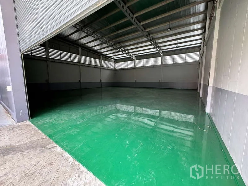 工厂 出租或出售在Lam Luk Ka, Pathum Thani - 卷闸门开启的仓库，通风墙体与大面积空旷地面。