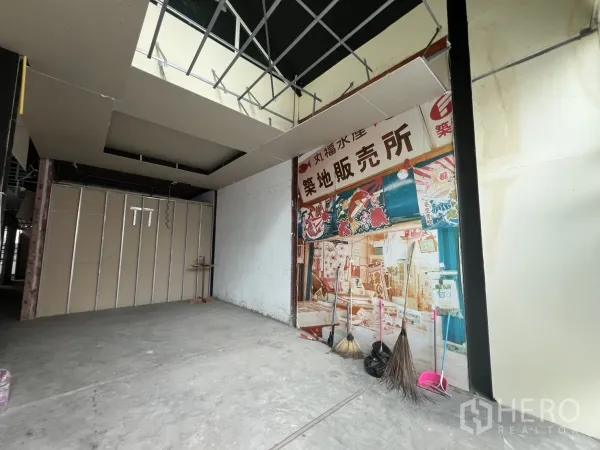 Retail Space for rent in Watthana, Bangkok - Double-height retail hall under renovation with exposed ceiling grid and a Japanese-style mural.