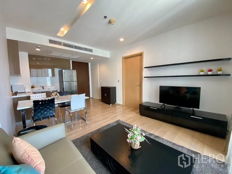 Condominium for rent in Khlong Toei, Bangkok - Living room with TV console, floating shelves and sofa facing the balcony.