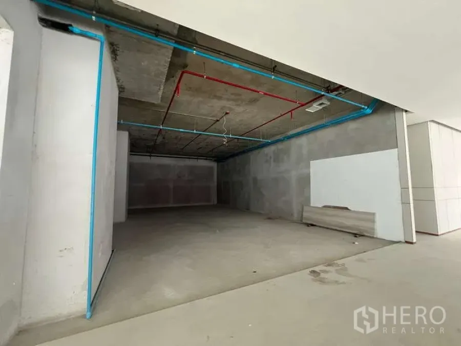 Retail Space for rent - Unfitted retail shell with wide open shopfront, exposed ceiling pipes, and concrete walls in Phaya Thai.