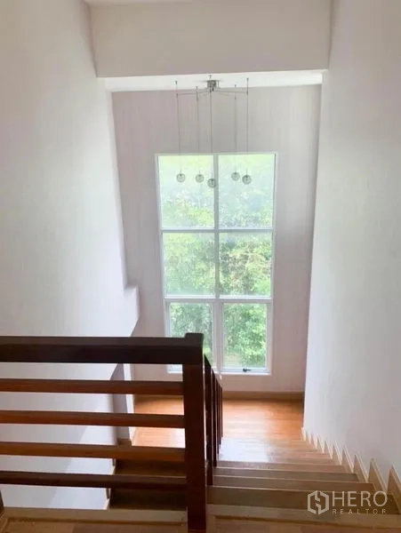 Detached House for sale in Saphan Sung, Bangkok - Staircase with wooden handrail and a tall picture window bringing in natural light.