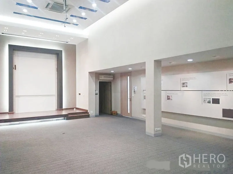 Office Space for rent in Suan Luang, Bangkok - Open presentation room with high ceiling, recessed lighting, and a small stage.