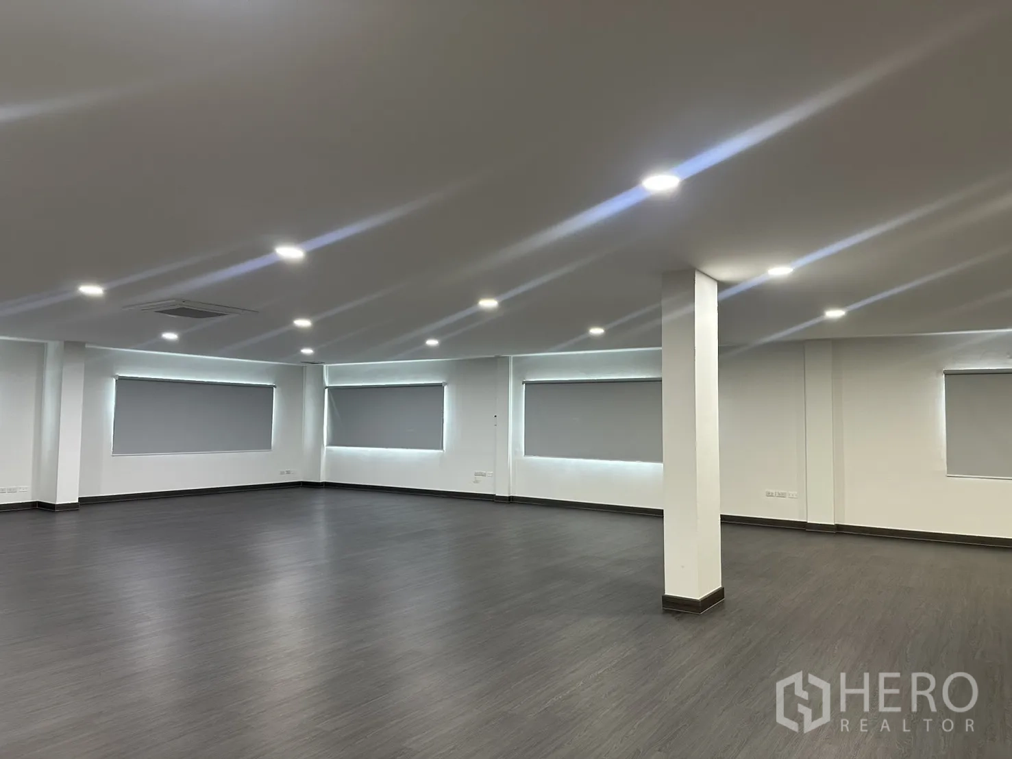 办公室 for rent in Yan Nawa, Bangkok - 办公室一角，带结构立柱、LED照明、天花空调出风口与遮光卷帘窗。