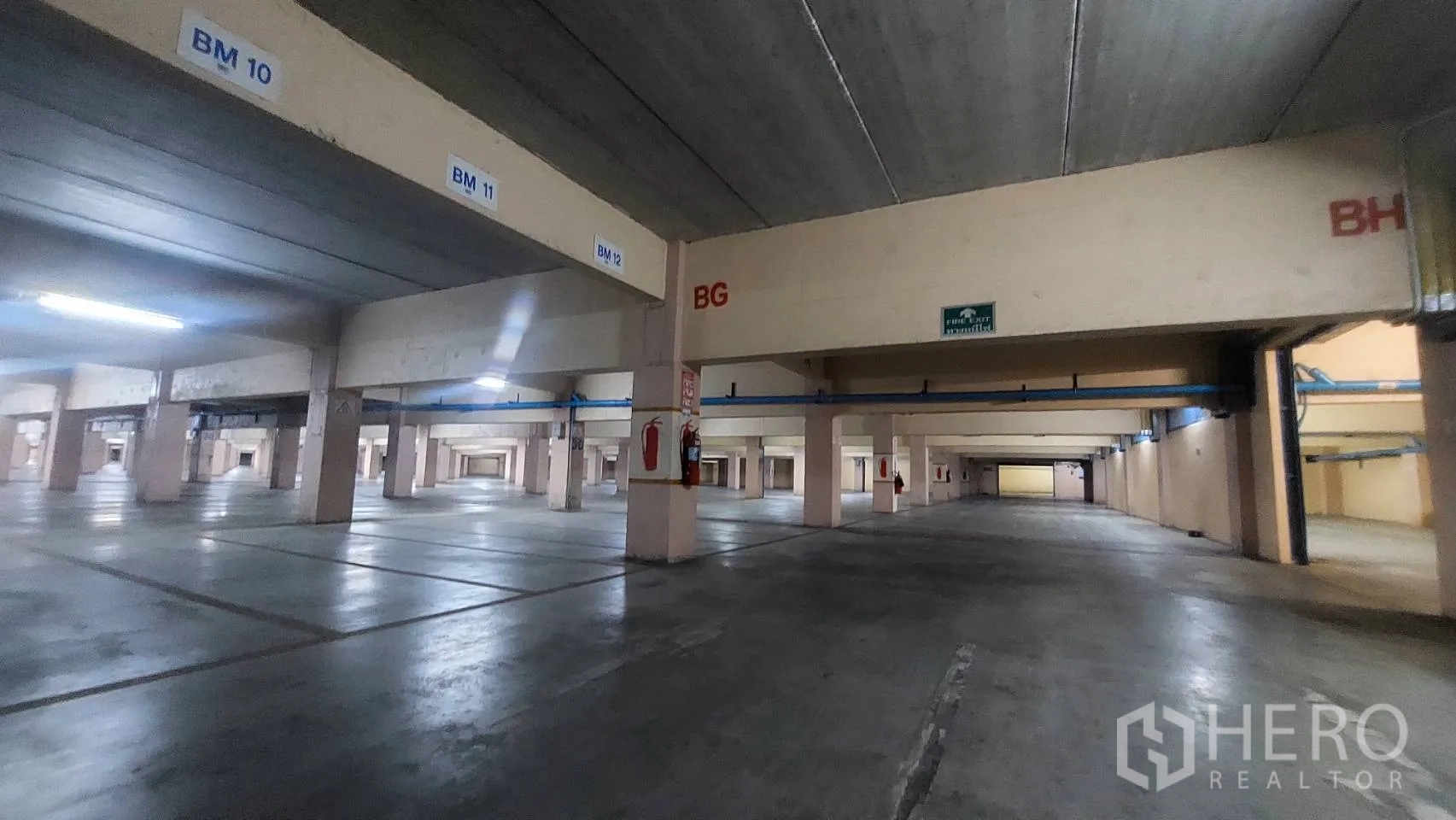 Warehouse for rent in Mueang Pathum Thani, Pathum Thani - Large covered parking area with numbered bays, concrete columns, and fire extinguishers.