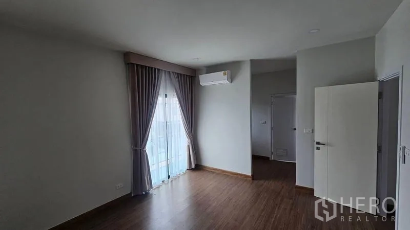 Detached House for rent in Bang Bo, Samut Prakan - Spacious upper floor room with air conditioner and balcony access.