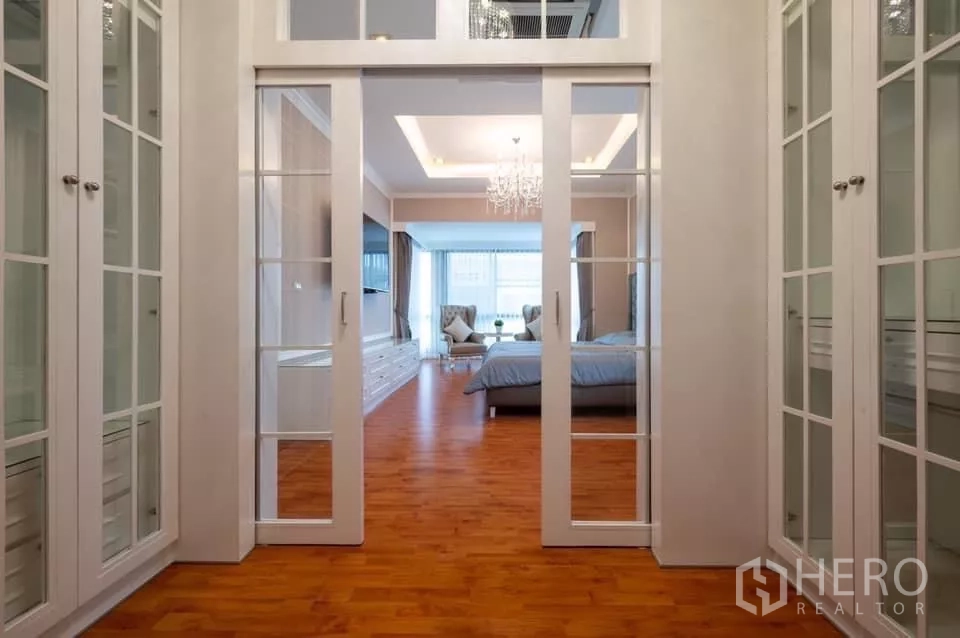 Detached House for rent in Prawet, Bangkok - Walk-through closet with glass-door cabinets leading to the bedroom suite.