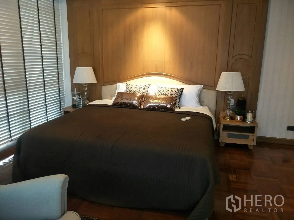 公寓 出租在Watthana, Bangkok - 主卧木饰面背景墙，软包床头与床侧台灯，棕色床品。