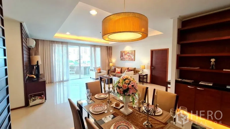 Apartment for rent in Khlong Toei, Bangkok - Open-plan dining and living room with pendant light, built-in shelving and balcony access.