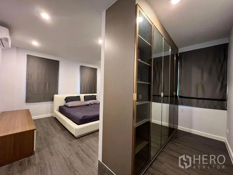 Detached House for sale in Bang Kruai, Nonthaburi - Spacious master suite with dark curtains, large glass‑door wardrobe and wood flooring.