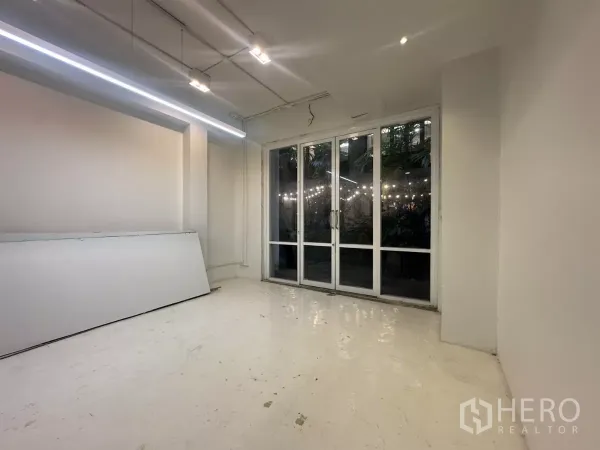 带办公室的家 出租在Pathum Wan, Bangkok - 明亮工作区，长条LED灯与落地玻璃门，对景绿植。