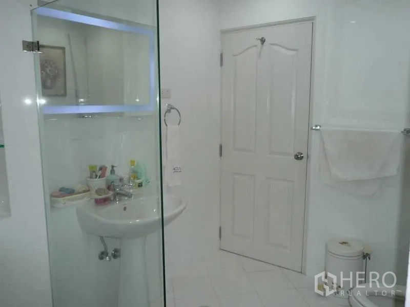 Detached House for rent in Bang Kapi, Bangkok - Bright white bathroom with glass shower enclosure and pedestal sink.
