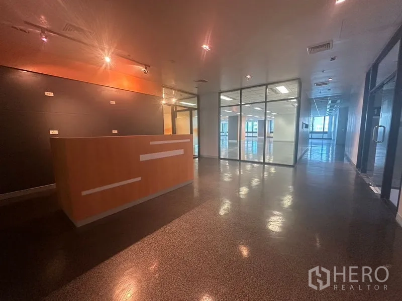 Office Space for rent in Khlong Toei, Bangkok - Reception area with wood counter, track lighting and glass partitions leading to an open office.
