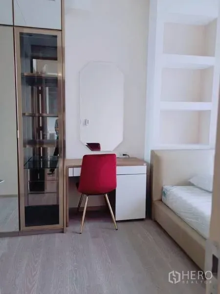 Condominium for rent or sale in Watthana, Bangkok - Bedroom corner with vanity desk, red chair, glass display cabinet and bed.