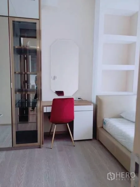 Condominium for rent or sale in Watthana, Bangkok - Bedroom corner with vanity desk, red chair, glass display cabinet and bed.