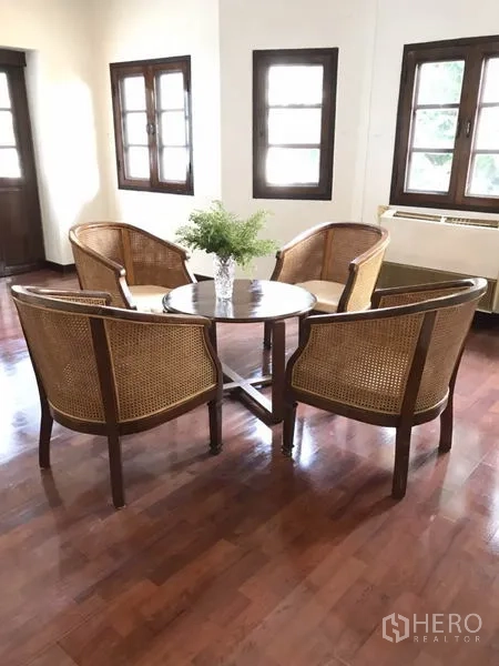 Detached House for rent in Phra Khanong, Bangkok - Cozy sitting corner with four rattan armchairs around a round table on wood flooring.