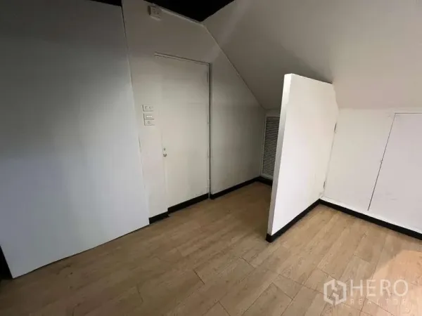 Retail Space for rent in Watthana, Bangkok - Compact back room with sloped ceiling, white walls, louvered doors, and laminate wood flooring.