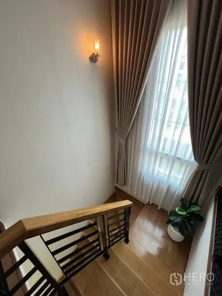 บ้าน ให้เช่าหรือขาย - บันไดไม้ข้างหน้าต่างสูงพร้อมผ้าม่าน