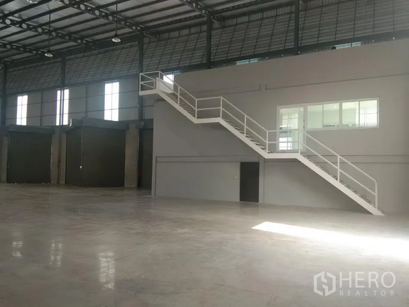 货栈 出租在Bang Phli, Samut Prakan - 仓库内夹层办公室与白色楼梯，临近多扇卷帘门俯瞰作业区