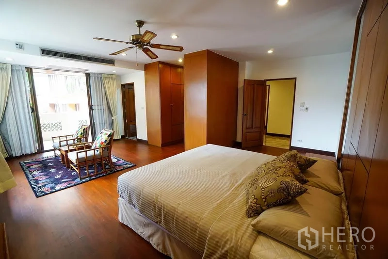 Apartment for rent in Watthana, Bangkok - Master bedroom with king bed, ceiling fan and sliding doors opening to a private balcony.