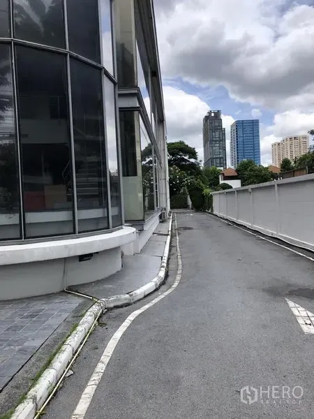 零售空间 出租在Watthana, Bangkok - 通往侧面的车道，旁为现代玻璃幕墙商铺，背景为通罗天际线。