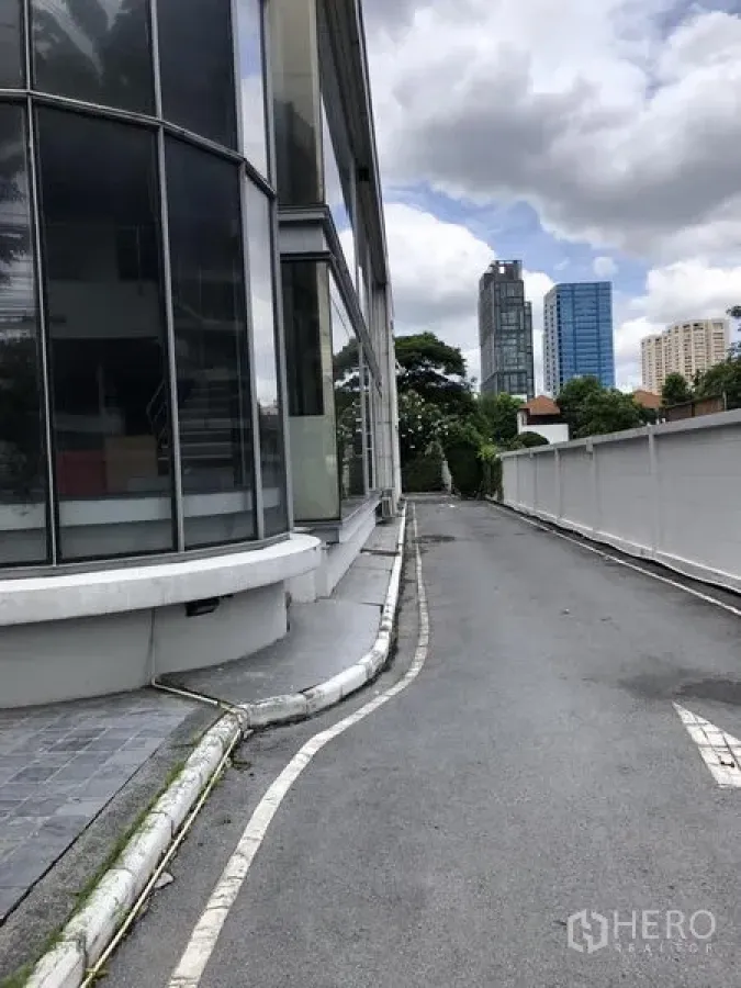 零售空间 出租在Watthana, Bangkok - 通往侧面的车道，旁为现代玻璃幕墙商铺，背景为通罗天际线。