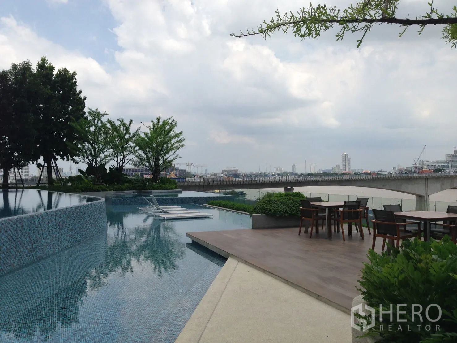 Condominium for rent in Bang Sue, Bangkok - Infinity-edge swimming pool with sun loungers and river-view deck.